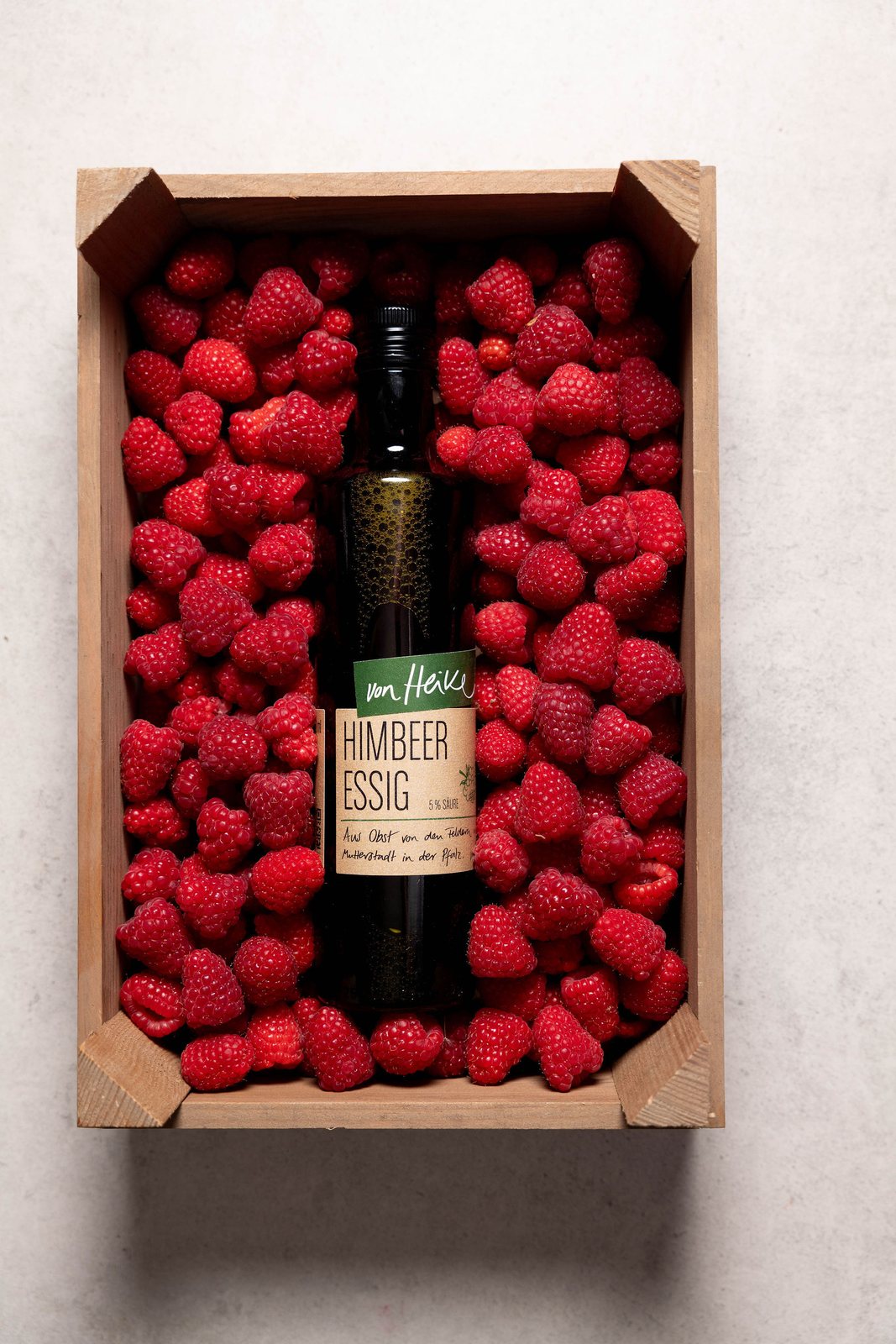 Himbeeren in der Holzkiste mit Sirupflasche